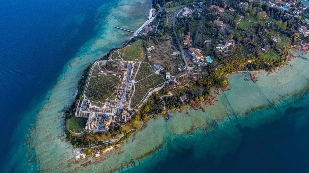 Aerial view of the Sirmione peninsula on Lake Garda, the castle and Roman villa ruins ringed by shallow turquoise water