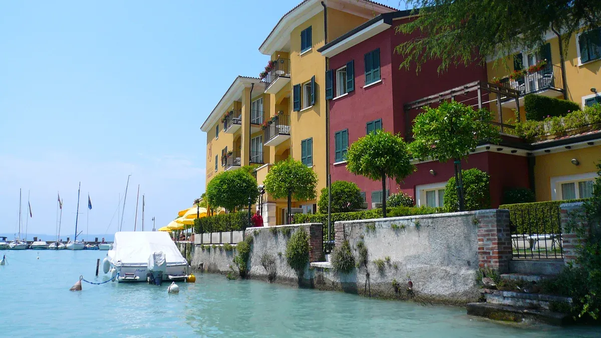 Small boats moored below yellow and red houses on the Sirmione waterfront